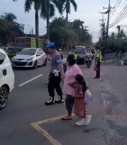 Kanit Provost Polsek Medan Tuntungan Bantu Warga dan Anak Sekolah Menyeberang Jalan